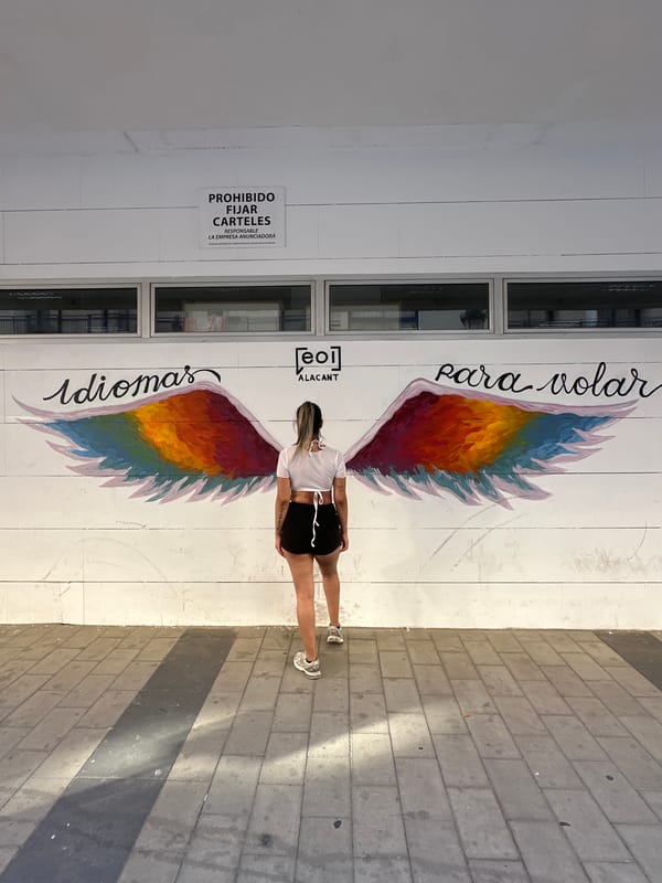 Woman poses with colorful wing mural in Alicante