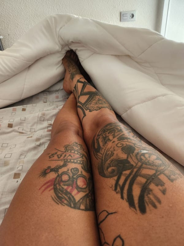 Tattooed person rests in bed in Murcia, Spain