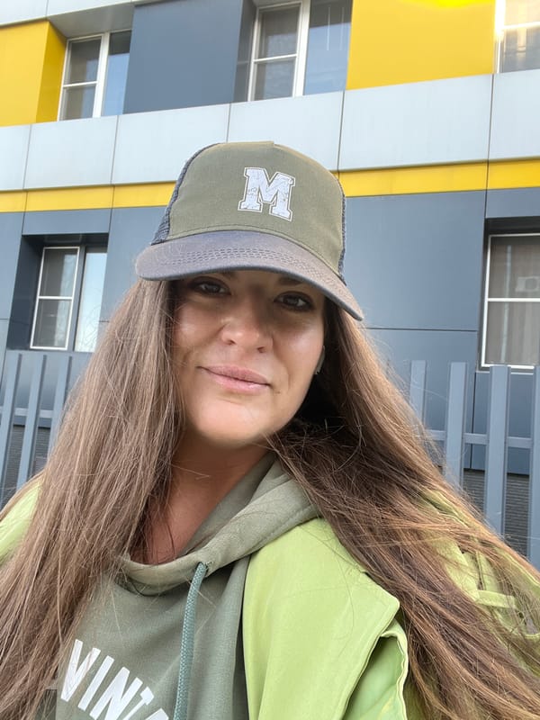 Woman in green cap stands outside modern building in Novosibirsk