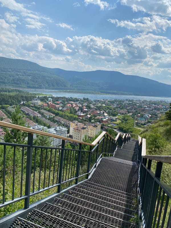 River town panorama from a hilltop overlook with bench and stairs
