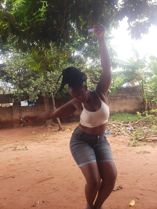 Person with braided hair holds object in rural area