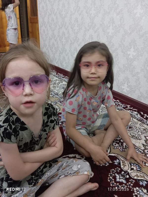 Two girls sit on rug in Bekabad, Uzbekistan