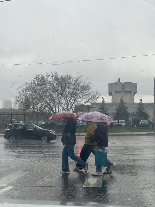Two pedestrians cross Moscow street during morning rain