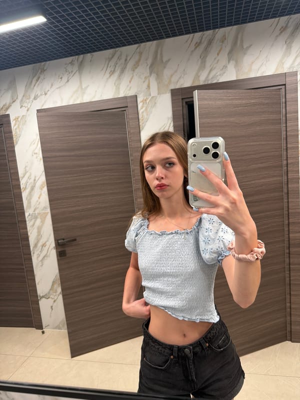 Restroom selfie session in a light blue smocked top