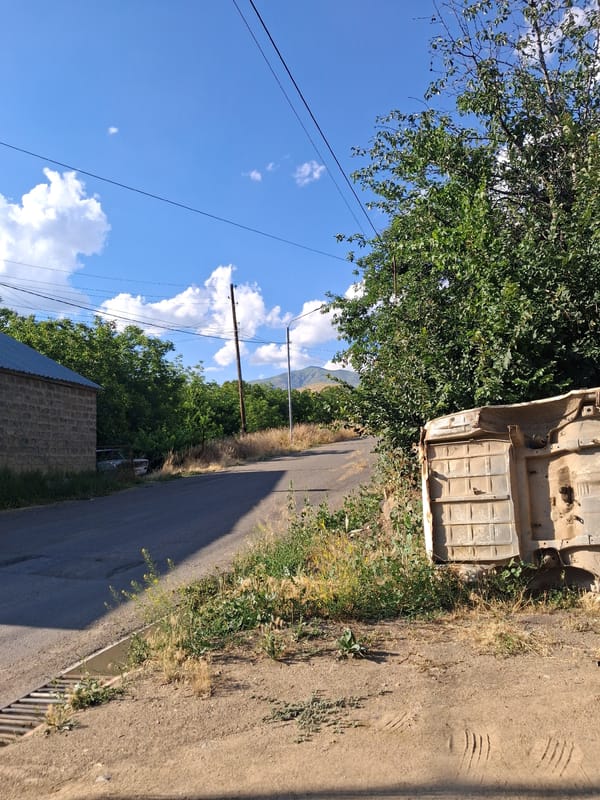 Abandoned vehicle chassis along a quiet rural road in Armenia