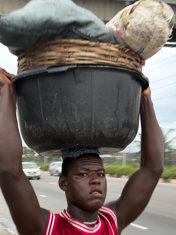 Head-carrying loads along a paved road in Igboefon