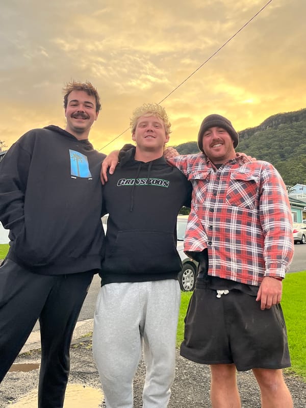 Three young men gather outdoors in Coledale, Australia