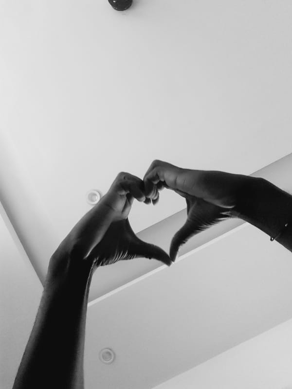 Hands up, face covered — quiet gestures against a white ceiling.