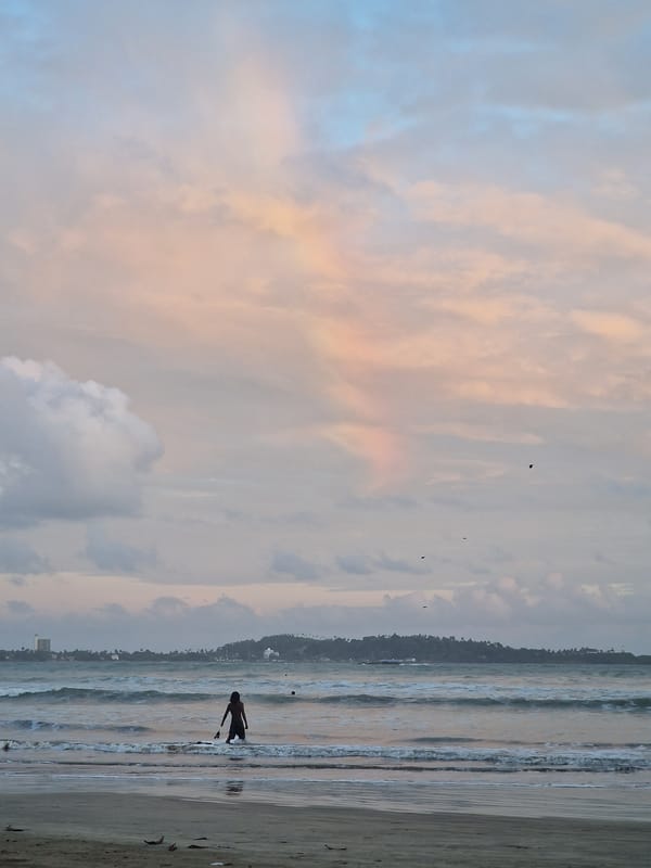 Person watches sunset on beach with colorful sky
