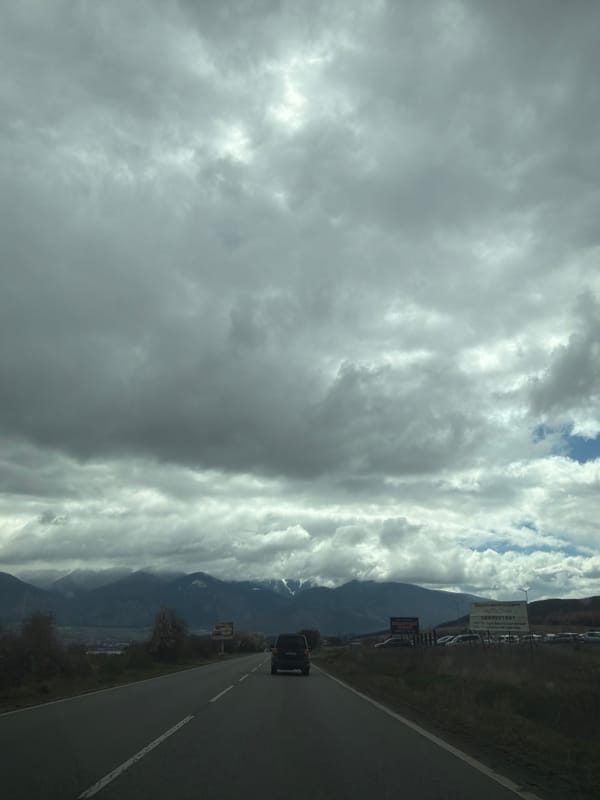 Car travels mountain road amid heavy clouds in Piperevo