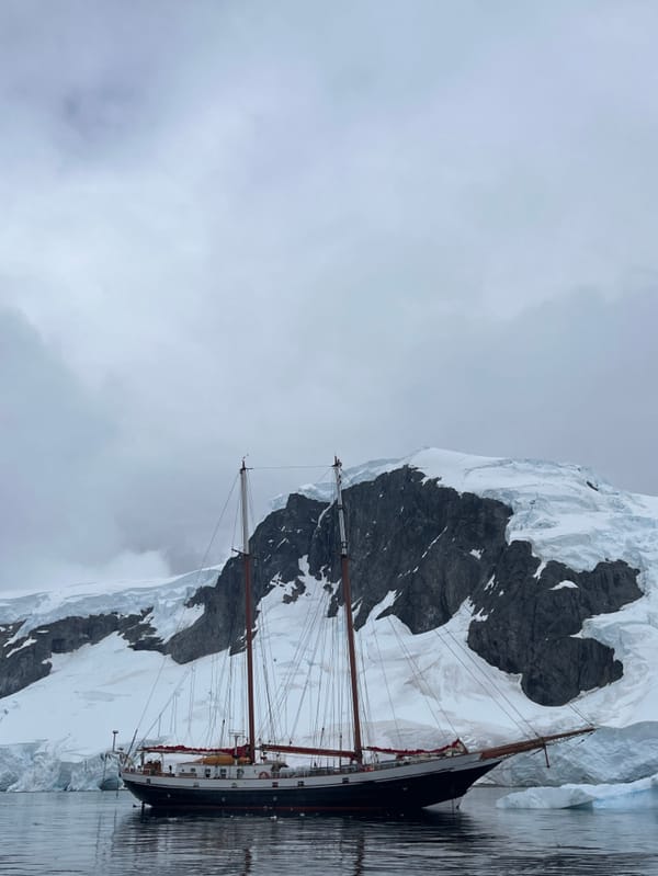 Sailing vessel spotted near Antarctic glaciers and rocky cliffs