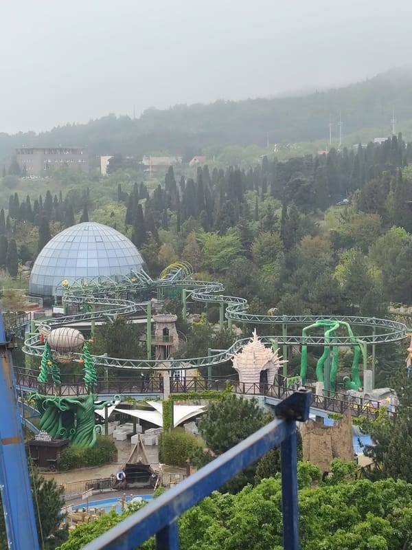 Theme park with green roller coaster and glass dome captured