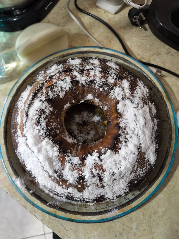 Powdered sugar bundt cake spotted on blue baking pan