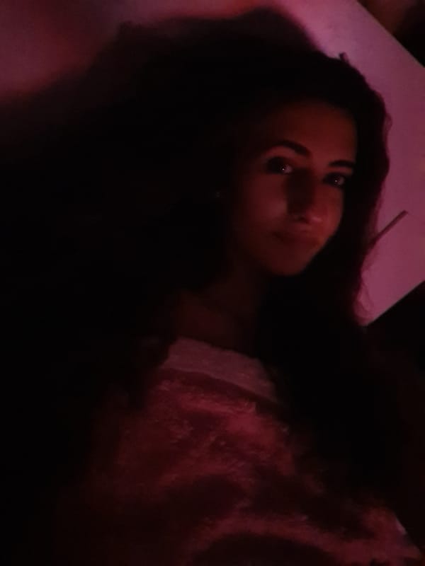Person relaxes in darkened room with screen light