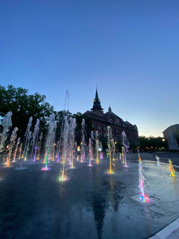 Evening fountain display illuminates historic Subotica under twilight moon
