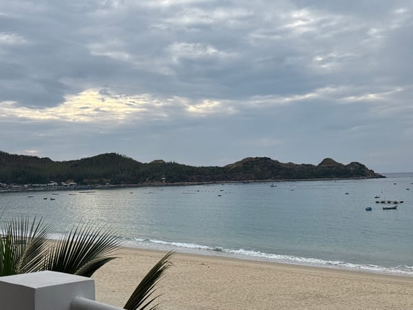 Overcast beach views with fishing boats and a distant island