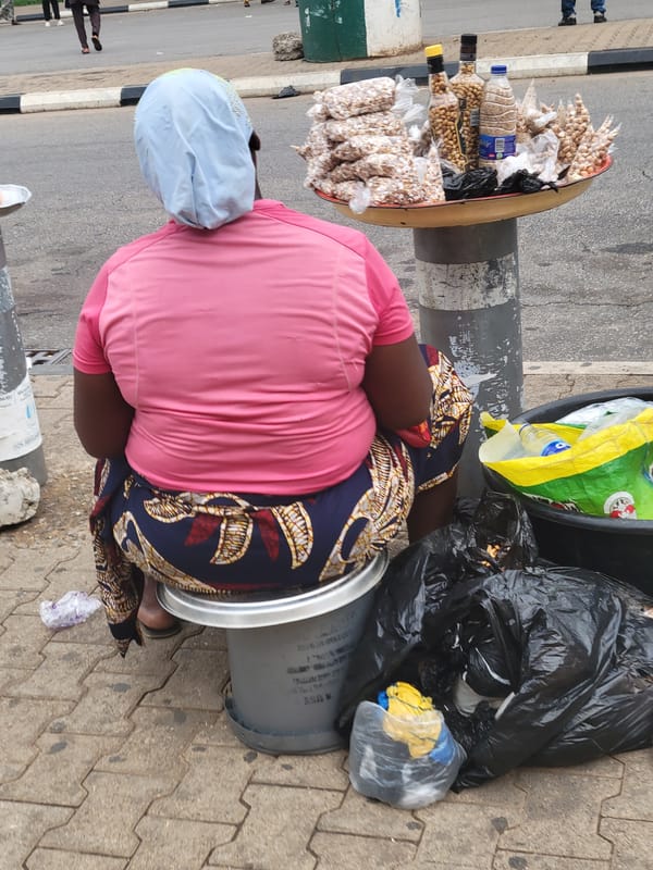 Street vendors conduct business along Abuja roadways during afternoon