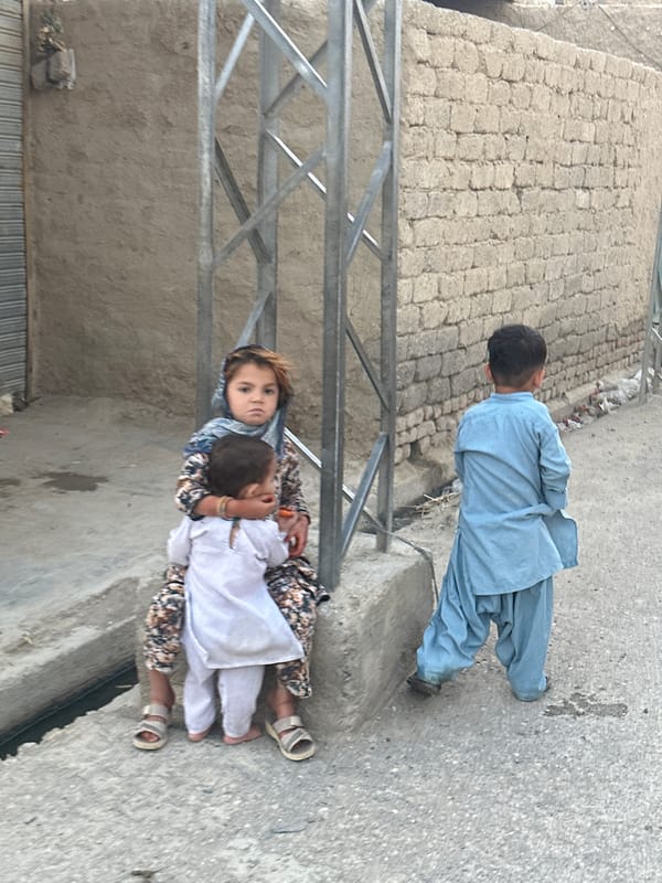 Kids on a Quetta street, traditional clothing, everyday moment.