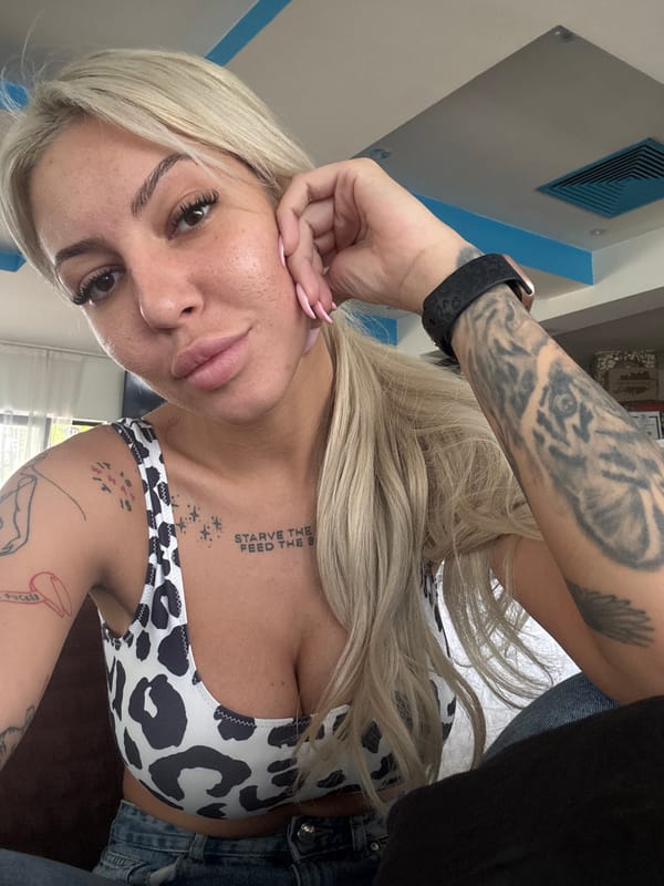 Tattooed woman in cow-print top observed resting indoors Plovdiv