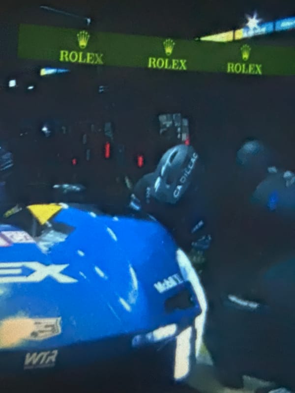 Night racing with blue Cadillac making pit stop