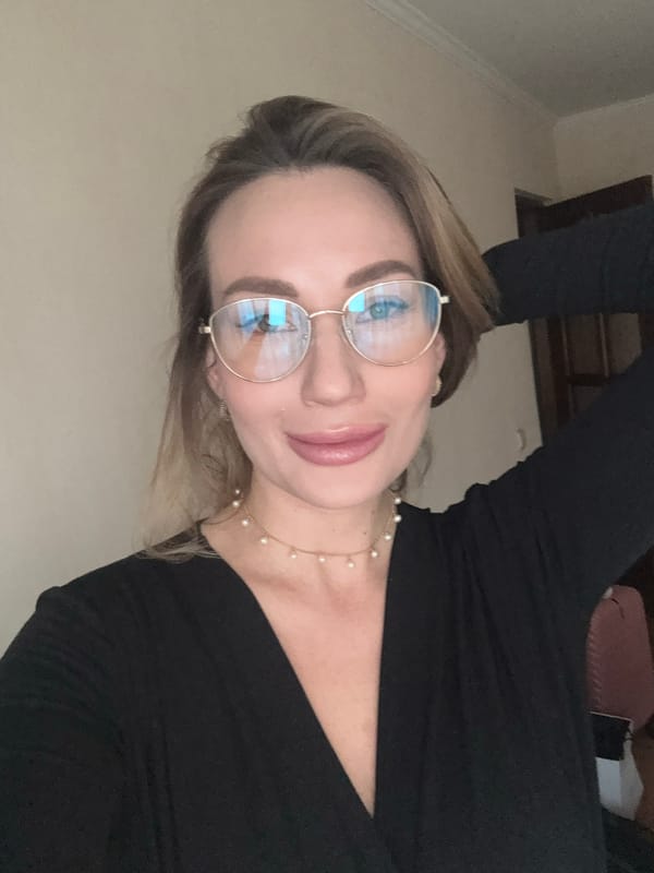 Woman photographed in gold-framed glasses, pearls in Riga