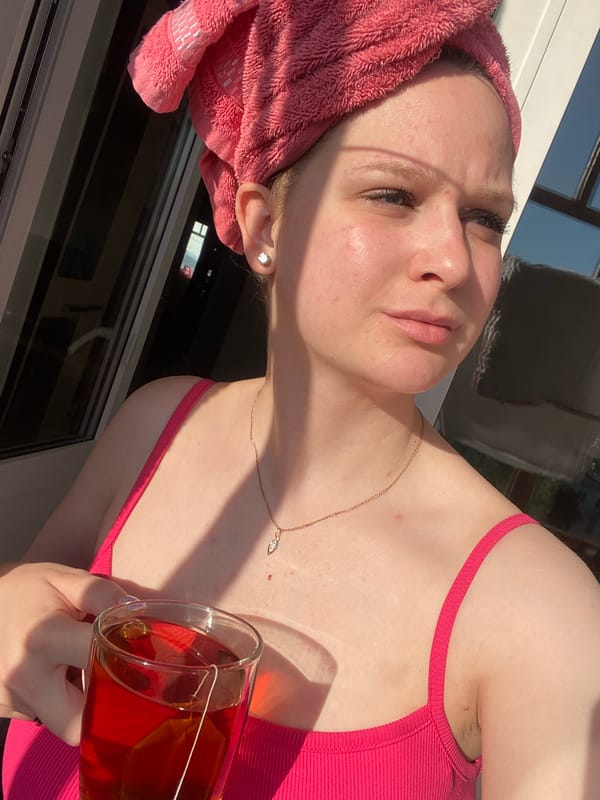 Woman enjoys morning tea by window in pink towel