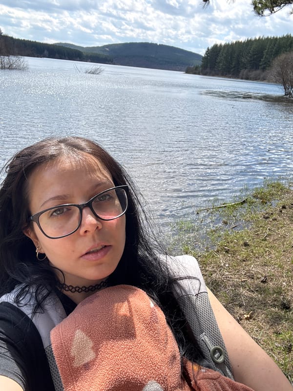Woman takes selfie at scenic Bulgarian lake surrounded by forest