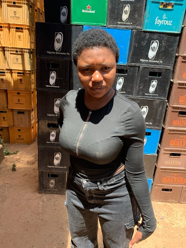 Woman poses among brewery crates in Gura Top Nigeria