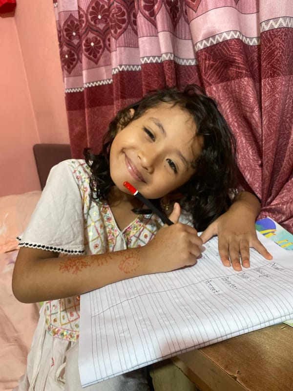 Writing in a notebook in Dhaka, henna-adorned arm on the page