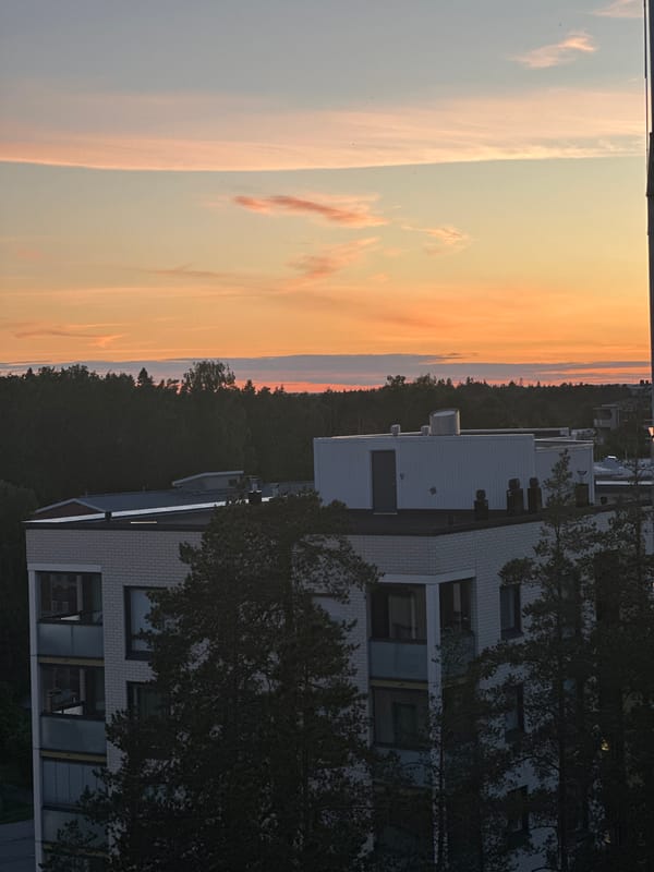 Crescent moon rises over city and forest at dusk