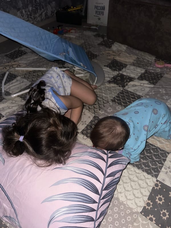 Two children rest on patchwork quilt in blue pajamas
