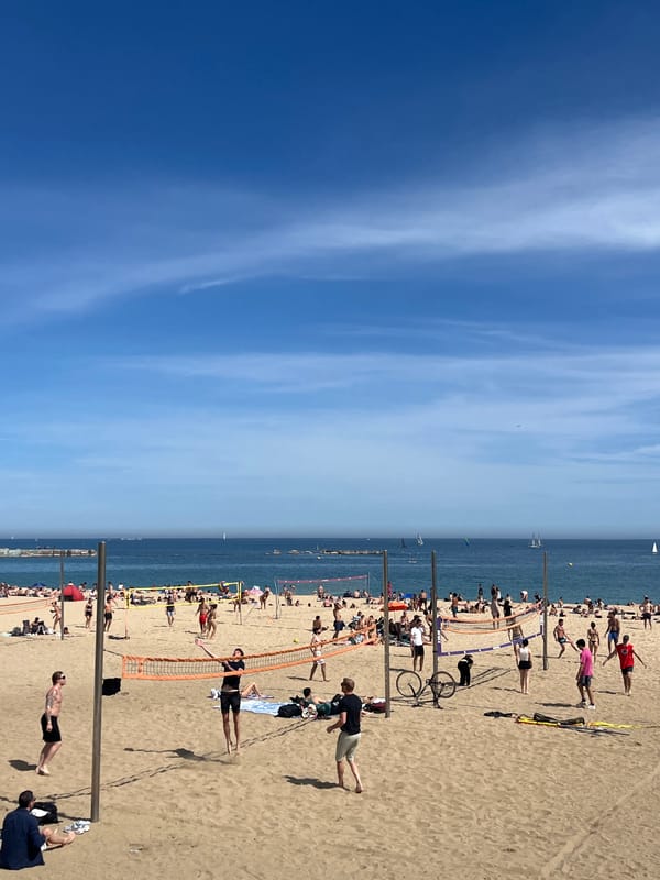 Busy afternoon observed at Barcelona's Barceloneta Beach under clear skies