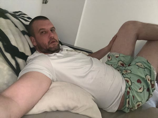 Man rests on bed in avocado shorts, Sofia