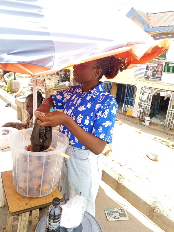 Woman packs food under umbrella in Gwong, Nigeria