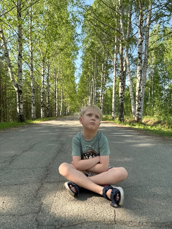 Boy sits on rural road in Банное, Russia