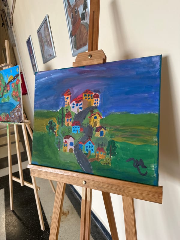 Oil painting of colorful village landscape displayed on easel