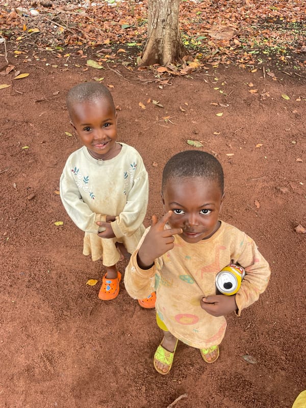 Children play and pose on red dirt in Ogbe, Nigeria