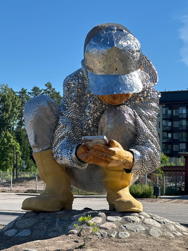 Paired squatting sculptures, metal and wood, in Tuusula public space