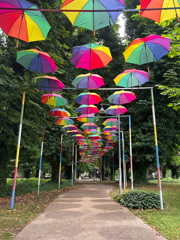 Rainbow umbrella tunnel installation along a Silistra park path