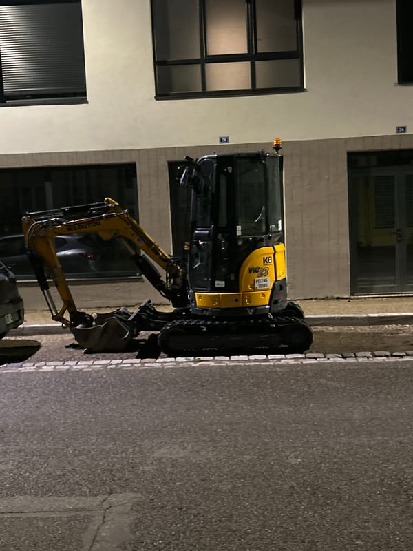 Nighttime street activity documented in Strasbourg with excavator, pedestrians