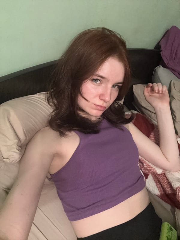 Woman rests on bed, looks at camera