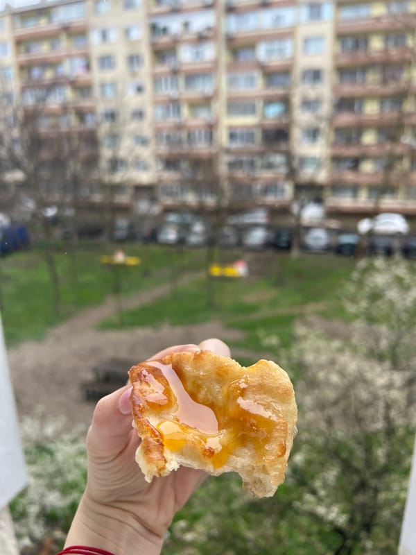 Person enjoys glazed pastry on residential street in Yambol