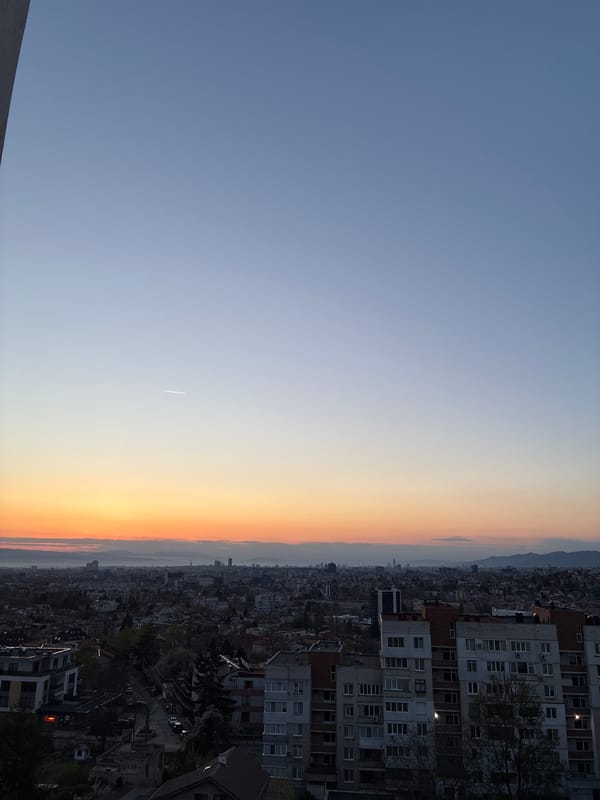 Dawn sky with contrail observed over Sofia residential district