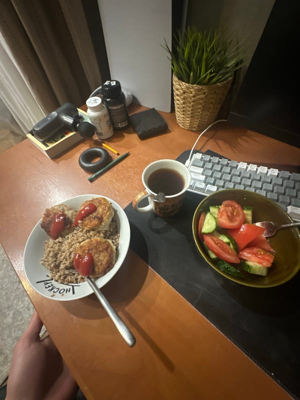 Young man working at cluttered desk with salad lunch
