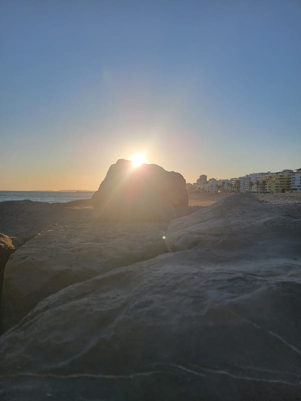Quarteira coastline at golden hour — rocks, sunset, beach life