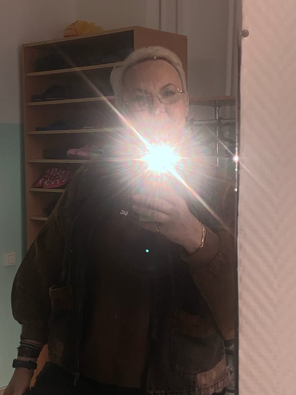 Elderly person in brown jacket observed in mirror reflection