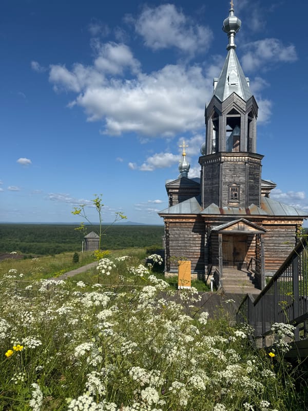 Wooden church and daisies on stairs in Cherdyn, Russia