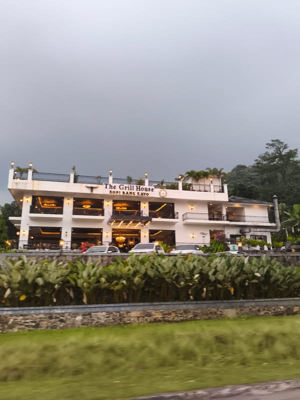 Morning traffic flows past cafes on tree-lined Babakan Madang road