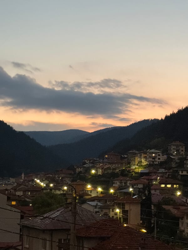 Hillside town silhouetted against a dusky orange sunset