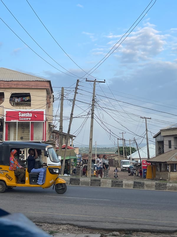 Nigerian city street buzzing with keke napeps, motos, and foot traffic